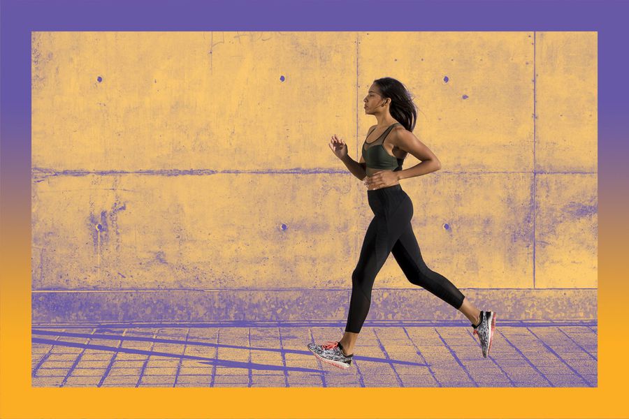 Young woman running along concrete wall in the city