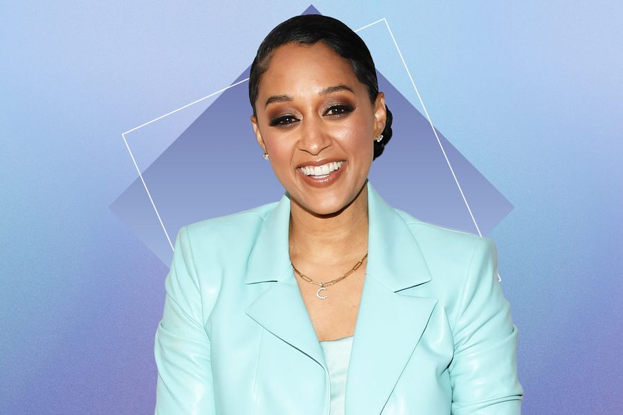 Tia Mowry wearing a turquoise blazer against a blue backgrounf