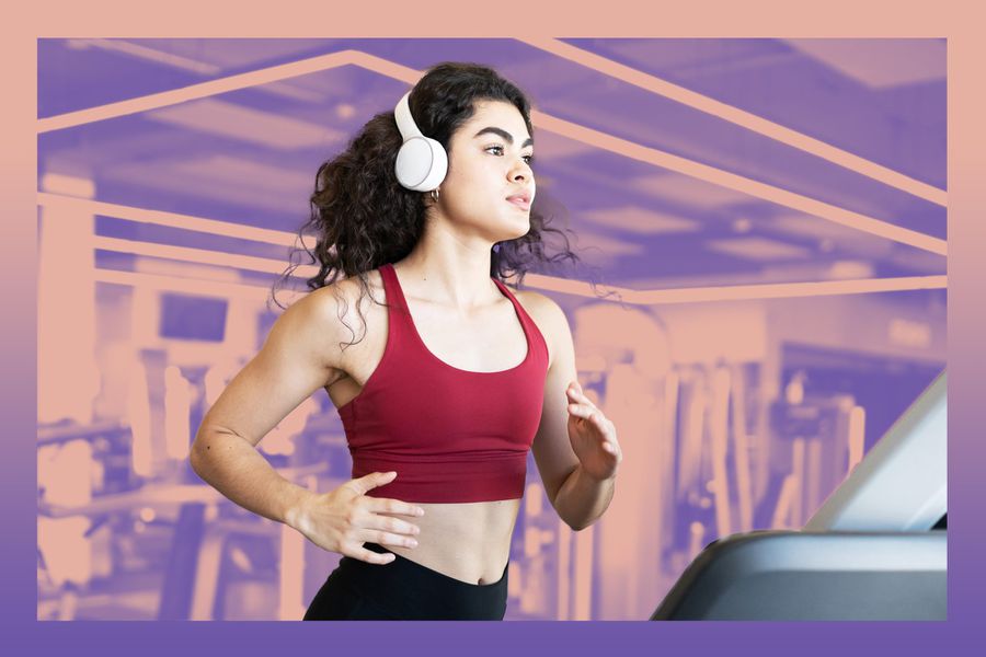 Woman with headphones running on treadmill at the gym