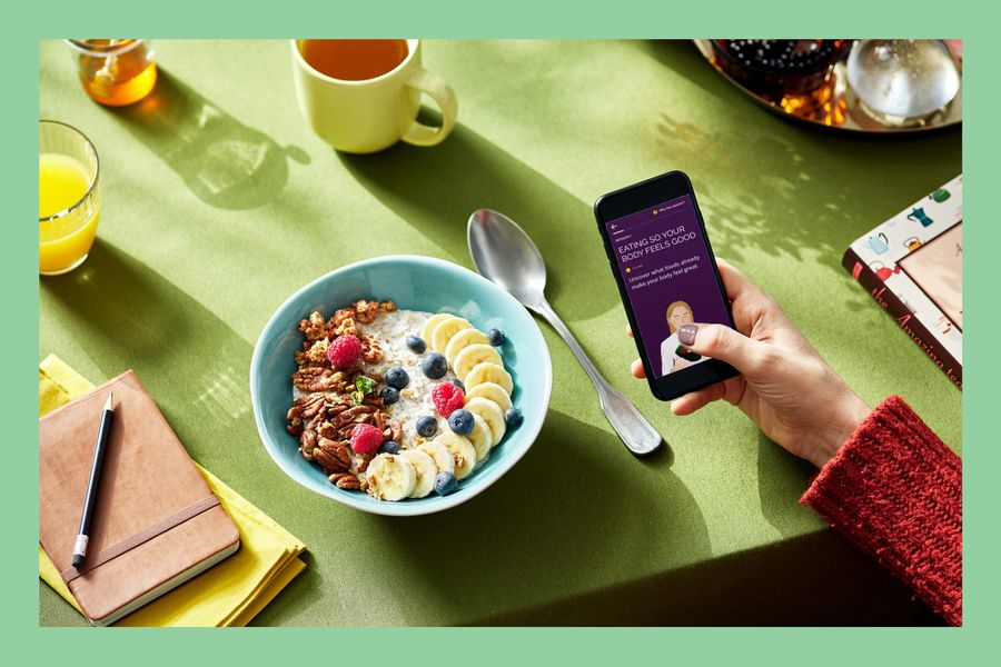 Woman with cell phone at breakfast looking at Way Health mindfulness app