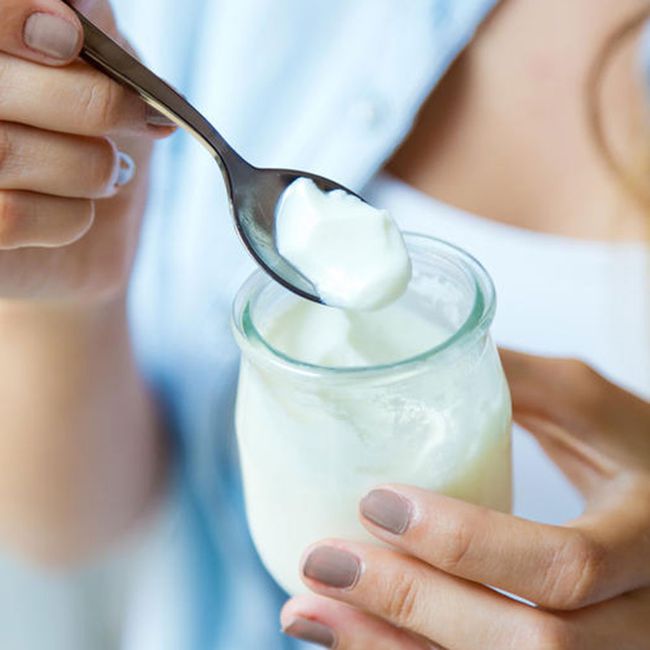 yogurt to help with bloating: a woman eats yogurt from a glass jar