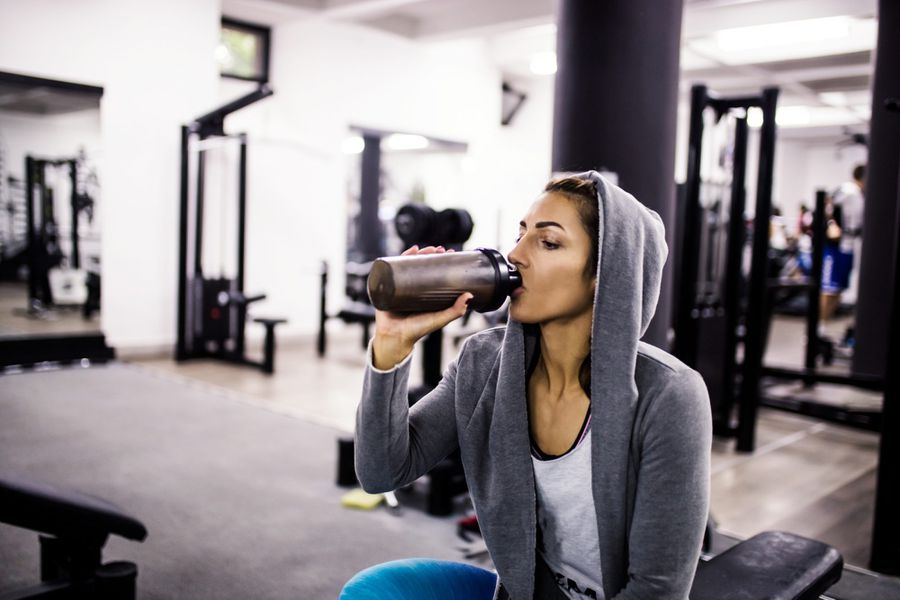 woman-drinking-protein-shake-before-or-after-workout-weight-room